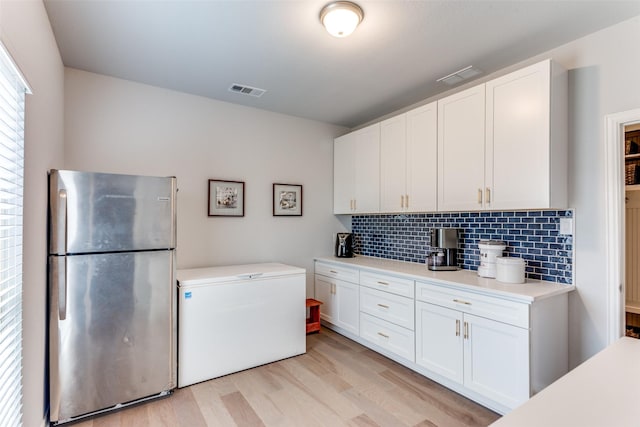 kitchen with light wood finished floors, light countertops, freestanding refrigerator, white cabinetry, and fridge