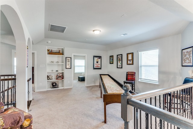 corridor with light carpet, vaulted ceiling, and built in features