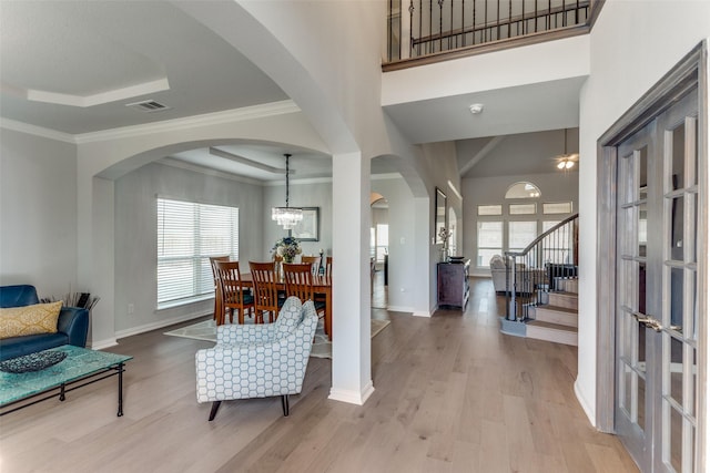 entryway with a chandelier, a raised ceiling, light hardwood / wood-style flooring, and a wealth of natural light