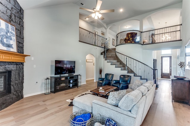 living room with arched walkways, a fireplace, a high ceiling, and wood finished floors