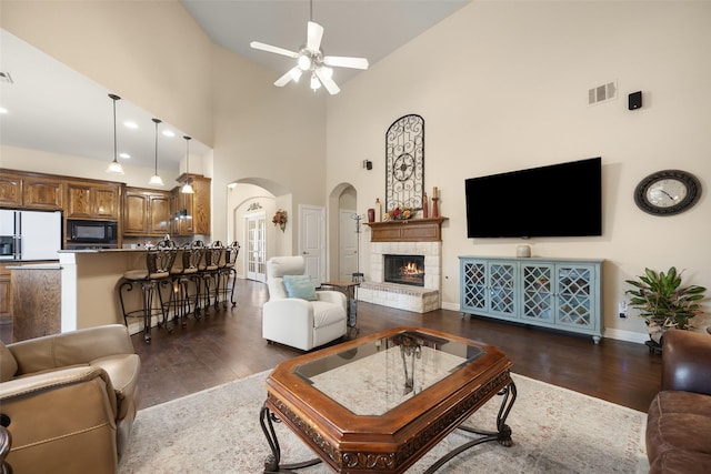 living room featuring ceiling fan, a towering ceiling, and dark hardwood / wood-style flooring