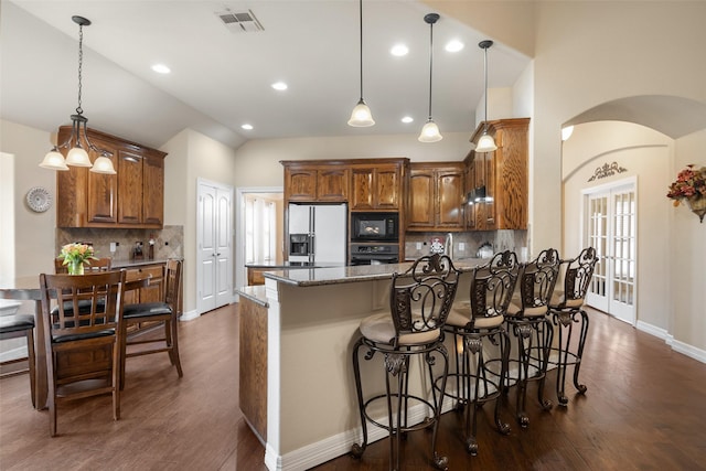 kitchen with pendant lighting, dark stone countertops, tasteful backsplash, and black appliances