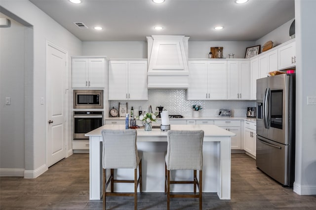 kitchen featuring stainless steel appliances, premium range hood, a center island, and white cabinetry