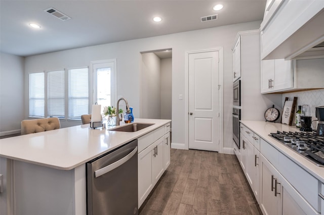 kitchen featuring white cabinetry, stainless steel appliances, sink, and a center island with sink