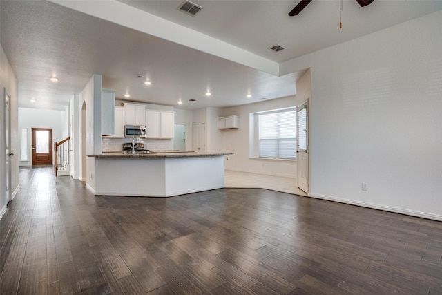 kitchen featuring ceiling fan, white cabinetry, light stone counters, tasteful backsplash, and dark hardwood / wood-style flooring