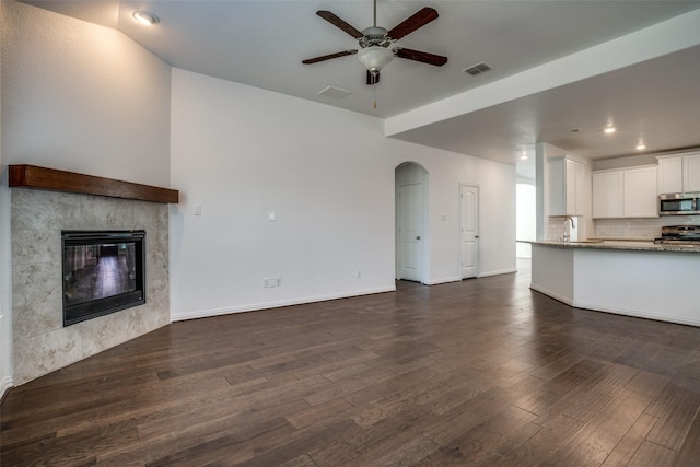 unfurnished living room featuring sink, a fireplace, dark hardwood / wood-style floors, and ceiling fan