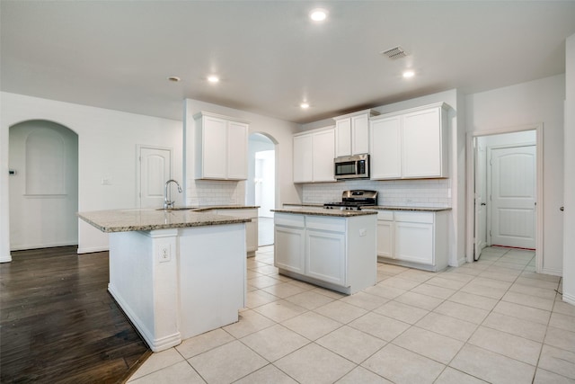 kitchen featuring stainless steel appliances, sink, a center island with sink, and white cabinets