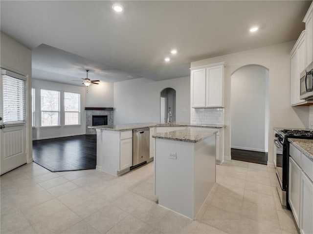 kitchen featuring white cabinetry, appliances with stainless steel finishes, kitchen peninsula, and a kitchen island