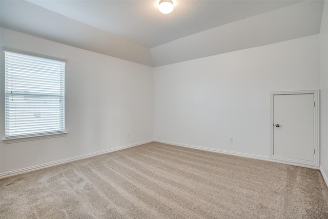 carpeted empty room with vaulted ceiling