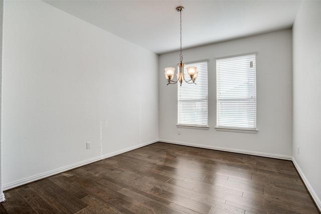 spare room with dark hardwood / wood-style floors and a chandelier