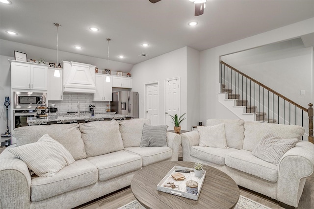 living room with ceiling fan, sink, and light hardwood / wood-style flooring