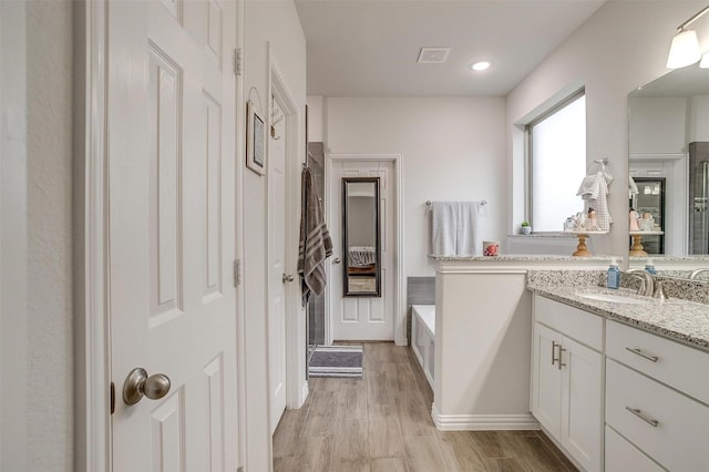 bathroom featuring vanity, hardwood / wood-style floors, and a tub