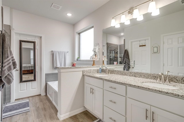 bathroom with vanity, independent shower and bath, and hardwood / wood-style floors