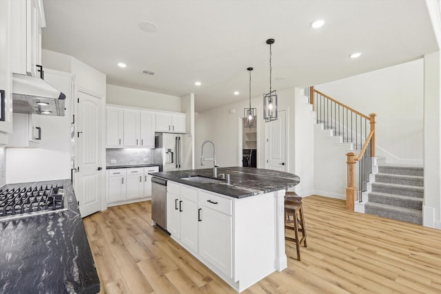 kitchen featuring stainless steel appliances, white cabinetry, a kitchen island with sink, and sink