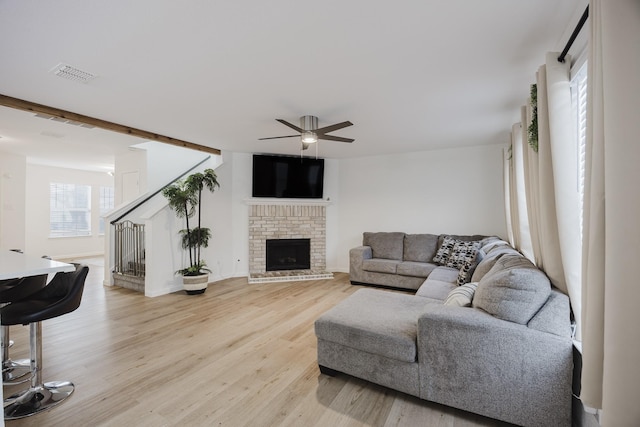 7935 Faithful Trl, Dallas, TX 75237 - living area featuring visible vents, light wood-type flooring, a ceiling fan, a fireplace, and stairs