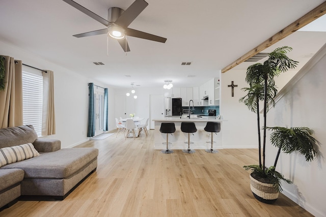 7935 Faithful Trl, Dallas, TX 75237 - living room featuring light wood-style flooring, baseboards, a ceiling fan, and visible vents