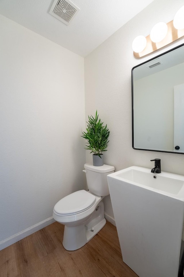 7935 Faithful Trl, Dallas, TX 75237 - bathroom with visible vents, toilet, wood finished floors, and baseboards