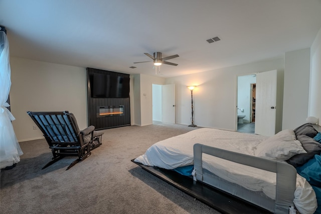 bedroom featuring connected bathroom, a fireplace, ceiling fan, and carpet flooring