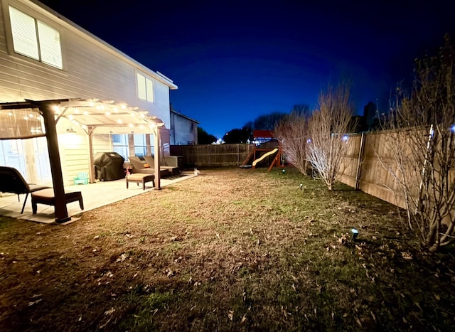 yard at night featuring a pergola, a patio area, and a playground