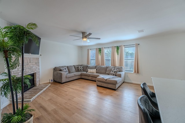 living room featuring a brick fireplace, ceiling fan, and light hardwood / wood-style flooring