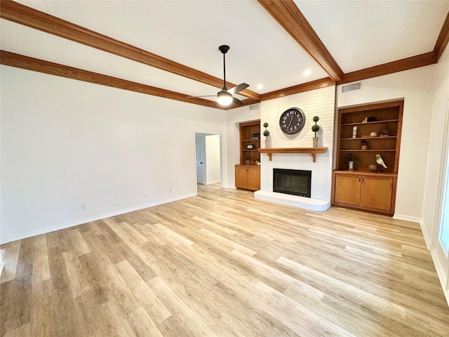 unfurnished living room featuring built in features, a large fireplace, ceiling fan, beam ceiling, and light hardwood / wood-style flooring