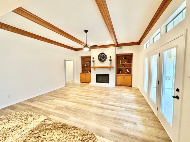 unfurnished living room with built in shelves, a fireplace, ceiling fan, and light wood-type flooring