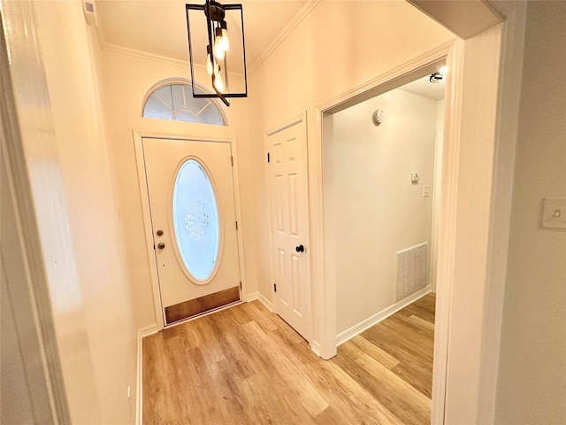 foyer featuring ornamental molding and light wood-type flooring