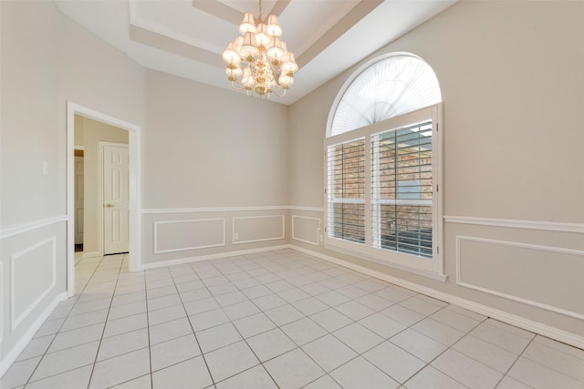 unfurnished room featuring light tile patterned flooring, an inviting chandelier, and a tray ceiling