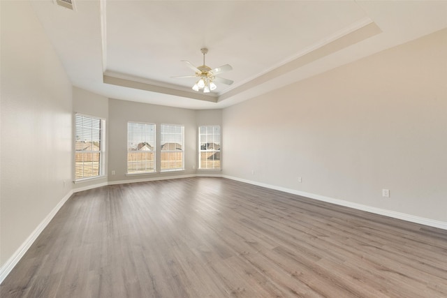 spare room with hardwood / wood-style flooring, crown molding, ceiling fan, and a tray ceiling