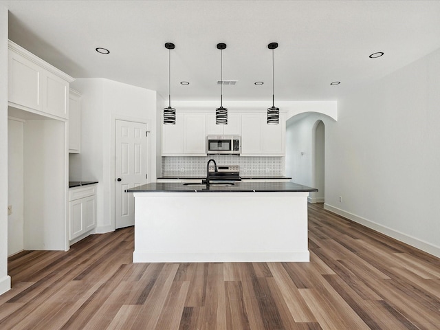 kitchen with stainless steel appliances, white cabinetry, a kitchen island with sink, and pendant lighting