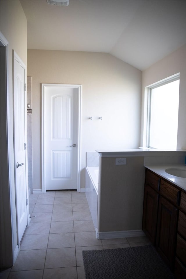 bathroom with vanity, a bath, tile patterned flooring, and vaulted ceiling