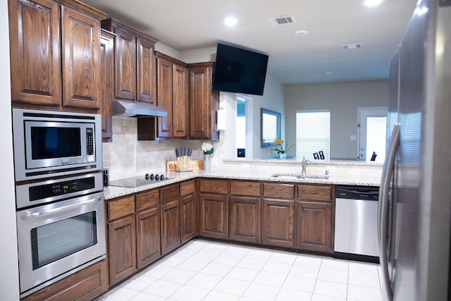 kitchen with light stone counters, appliances with stainless steel finishes, sink, and decorative backsplash