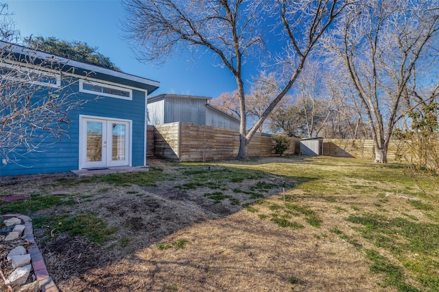 view of yard featuring fence, an outbuilding, and french doors