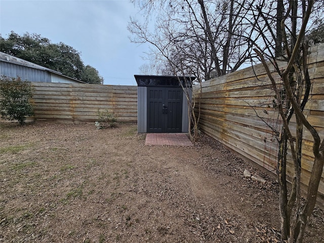 view of yard with a storage shed, a fenced backyard, and an outdoor structure