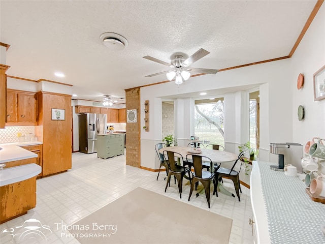 dining area with ornamental molding, ceiling fan, and a textured ceiling