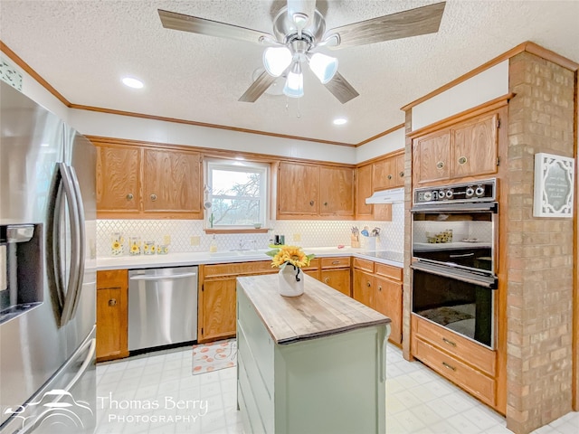 kitchen featuring crown molding, butcher block counters, backsplash, a center island, and black appliances