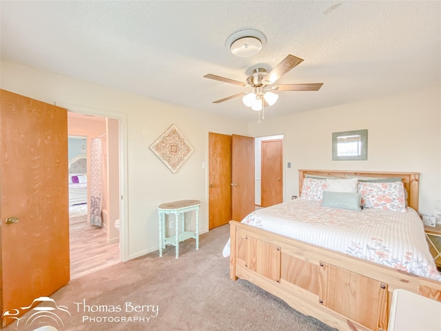 bedroom featuring light carpet, a textured ceiling, and ceiling fan