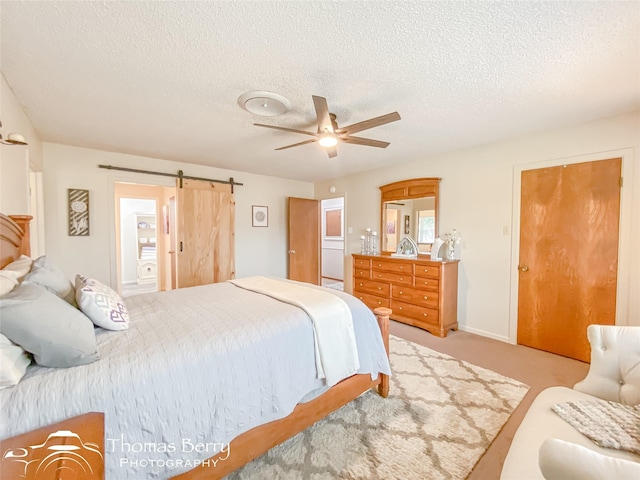 bedroom with a barn door, light colored carpet, a textured ceiling, and ceiling fan