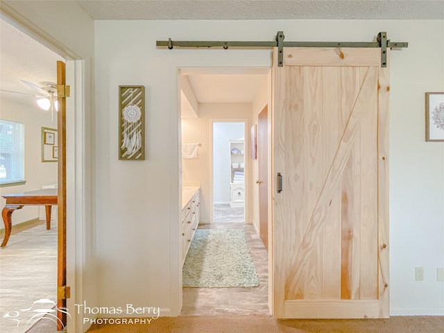 hall featuring a barn door and a textured ceiling