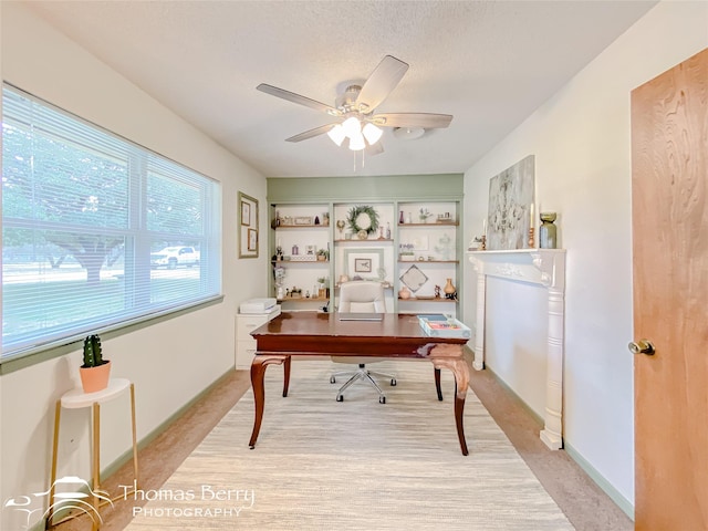 office area with a textured ceiling, light colored carpet, and ceiling fan