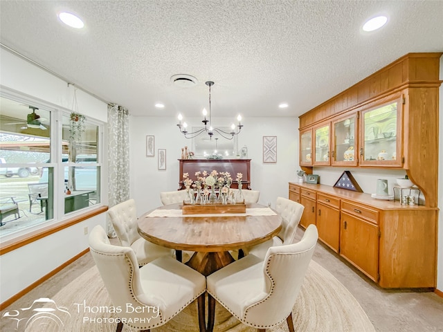 carpeted dining area with ceiling fan with notable chandelier and a textured ceiling