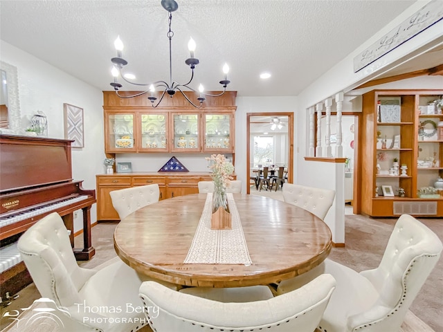 dining area featuring ceiling fan with notable chandelier and a textured ceiling