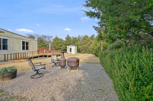 view of yard with a wooden deck, a storage shed, and an outdoor fire pit