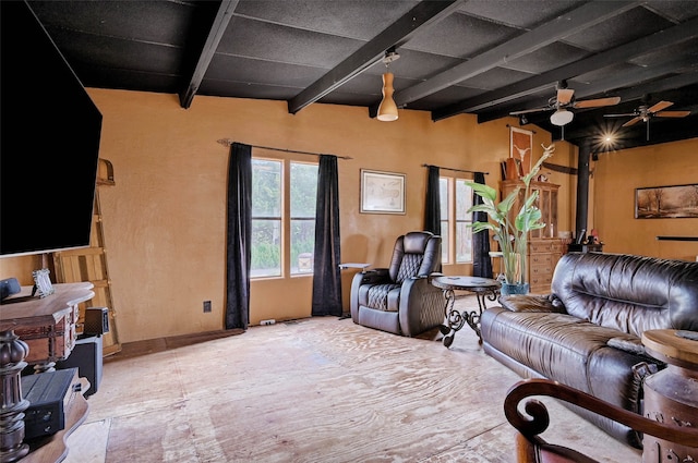 living room featuring ceiling fan, beamed ceiling, and a wood stove