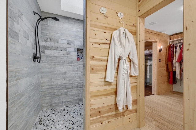 bathroom featuring a tile shower and wooden walls