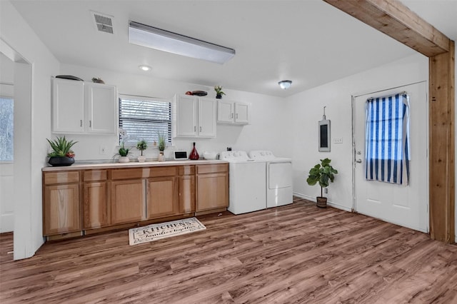 laundry room with independent washer and dryer, light hardwood / wood-style flooring, and cabinets