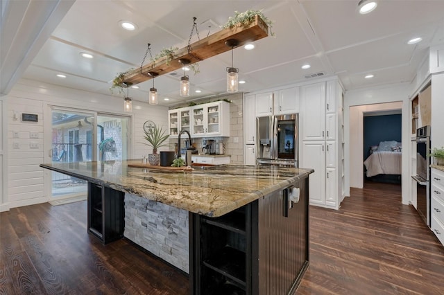 kitchen with white cabinetry, pendant lighting, stainless steel appliances, a large island, and light stone countertops