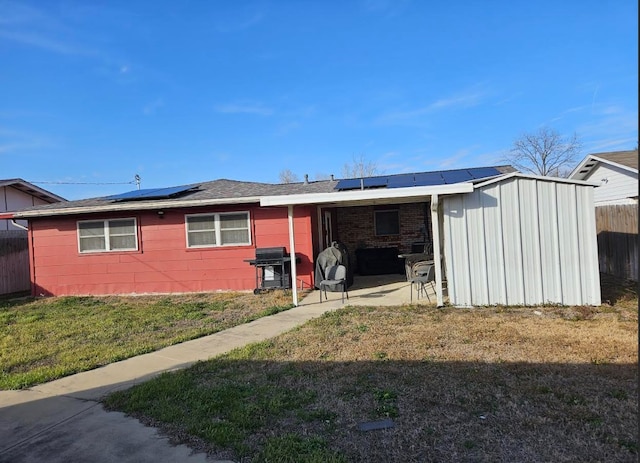 back of house with roof mounted solar panels and a patio area