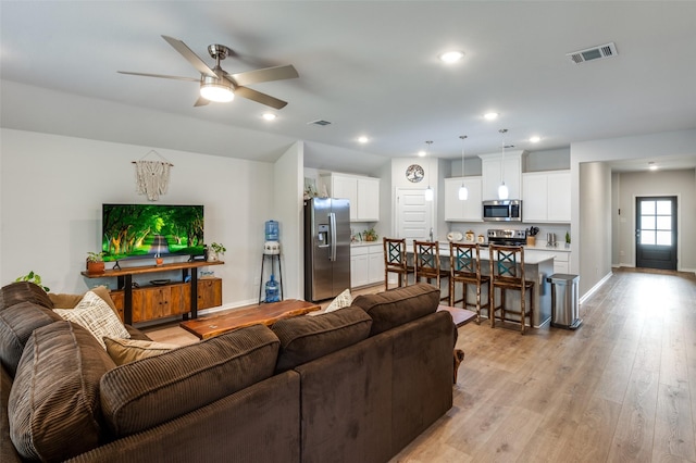 living area with light wood-type flooring, visible vents, baseboards, and recessed lighting