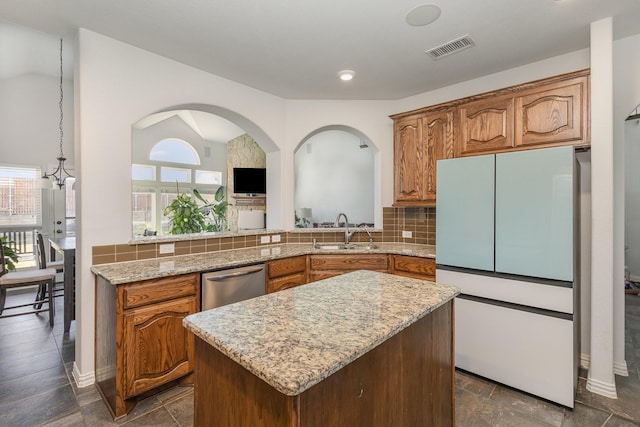 kitchen with sink, backsplash, white fridge, a center island, and stainless steel dishwasher